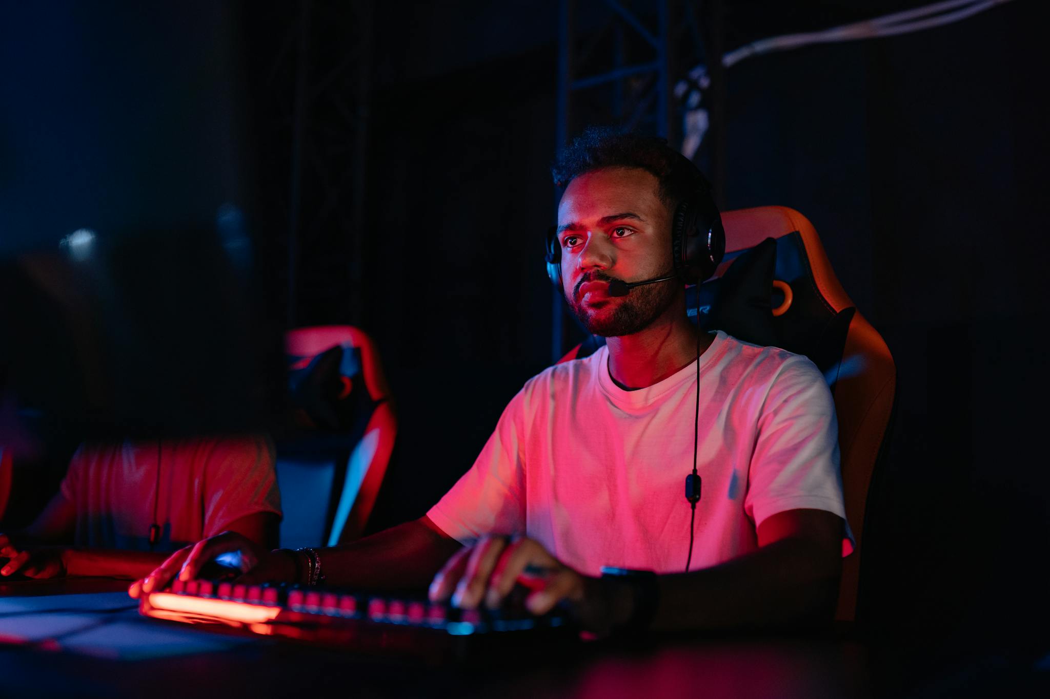 A young man focuses intensely while playing in an online gaming tournament, wearing a headset.